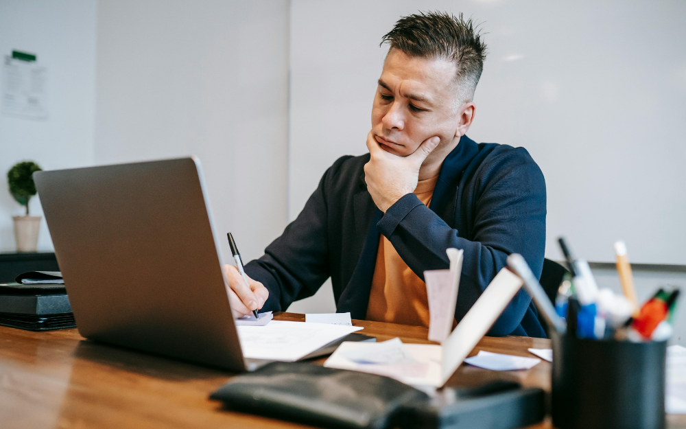 A Man at A Desk Looking at A Laptop — Midcoast Financial Planning Group in Tuncurry, NSW
