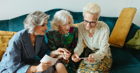 Three Women on A Blue Couch, Looking at Photos — Midcoast Financial Planning Group in Tuncurry, NSW