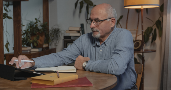 Older Adult With Glasses Using A Tablet — Midcoast Financial Planning Group in Tuncurry, NSW