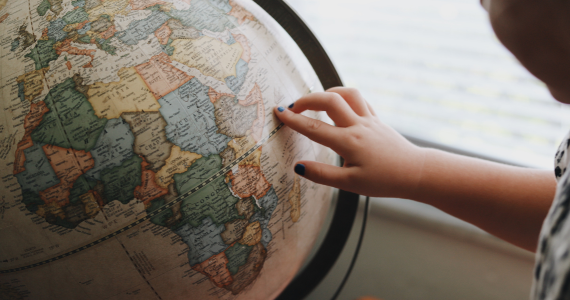 Child's Hand Pointing at A Globe — Midcoast Financial Planning Group in Tuncurry, NSW