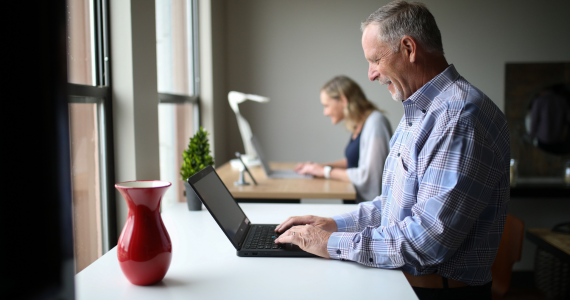 Man Typing on Laptop at Standing Desk — Midcoast Financial Planning Group in Tuncurry, NSW