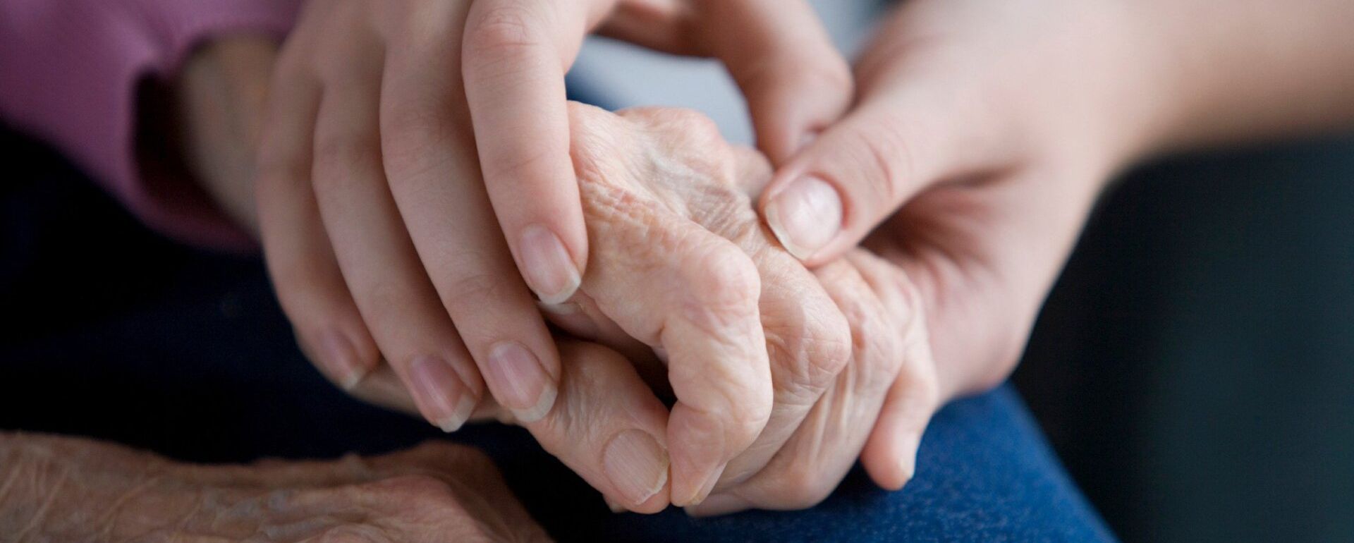 A woman is holding the hand of an older woman.