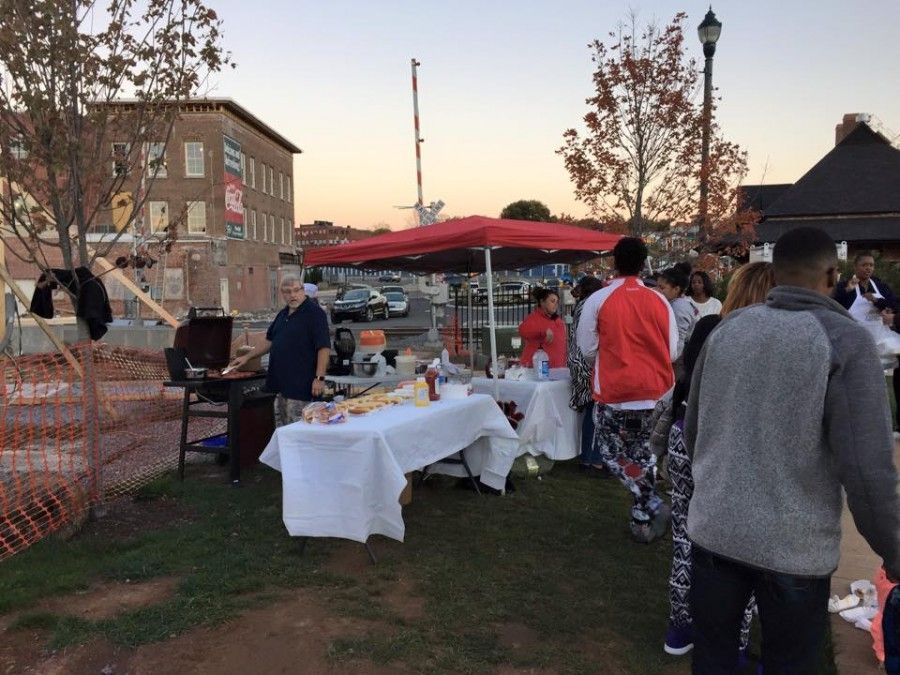 A group of people are standing around tables in a park.