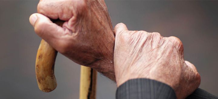 A close up of an elderly person 's hands holding a cane.