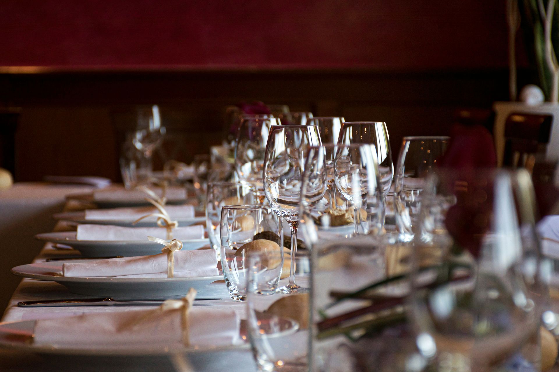 A long table with plates and wine glasses on it.