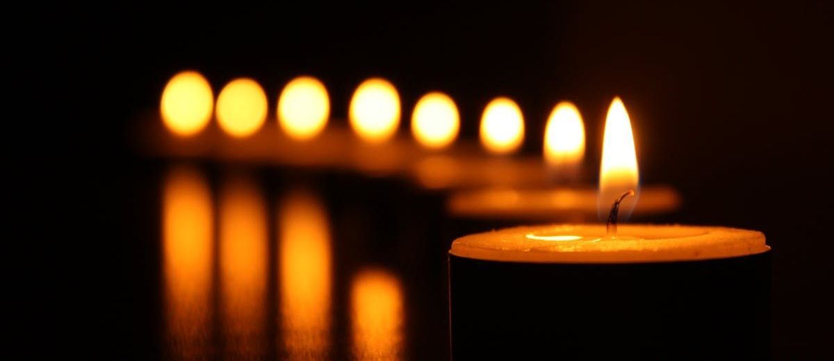 A row of lit candles in a dark room.