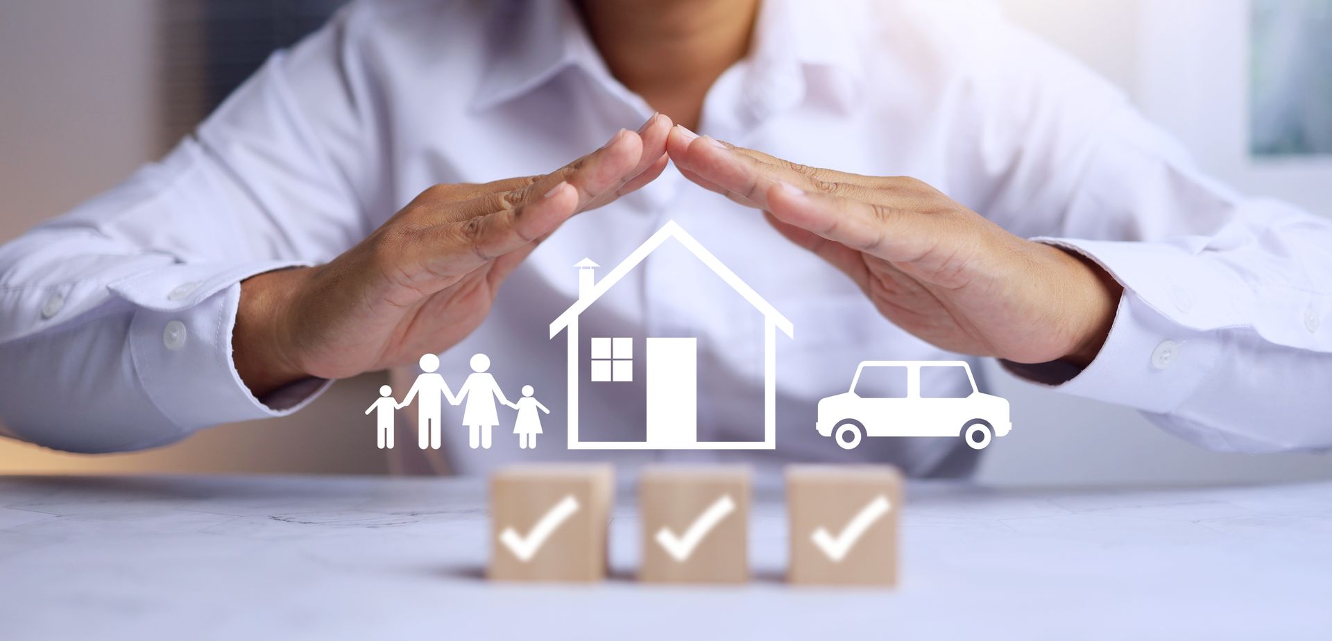 Hands hover over icons of a family, a house, and a car, with three wooden blocks marked with checkmarks in front.