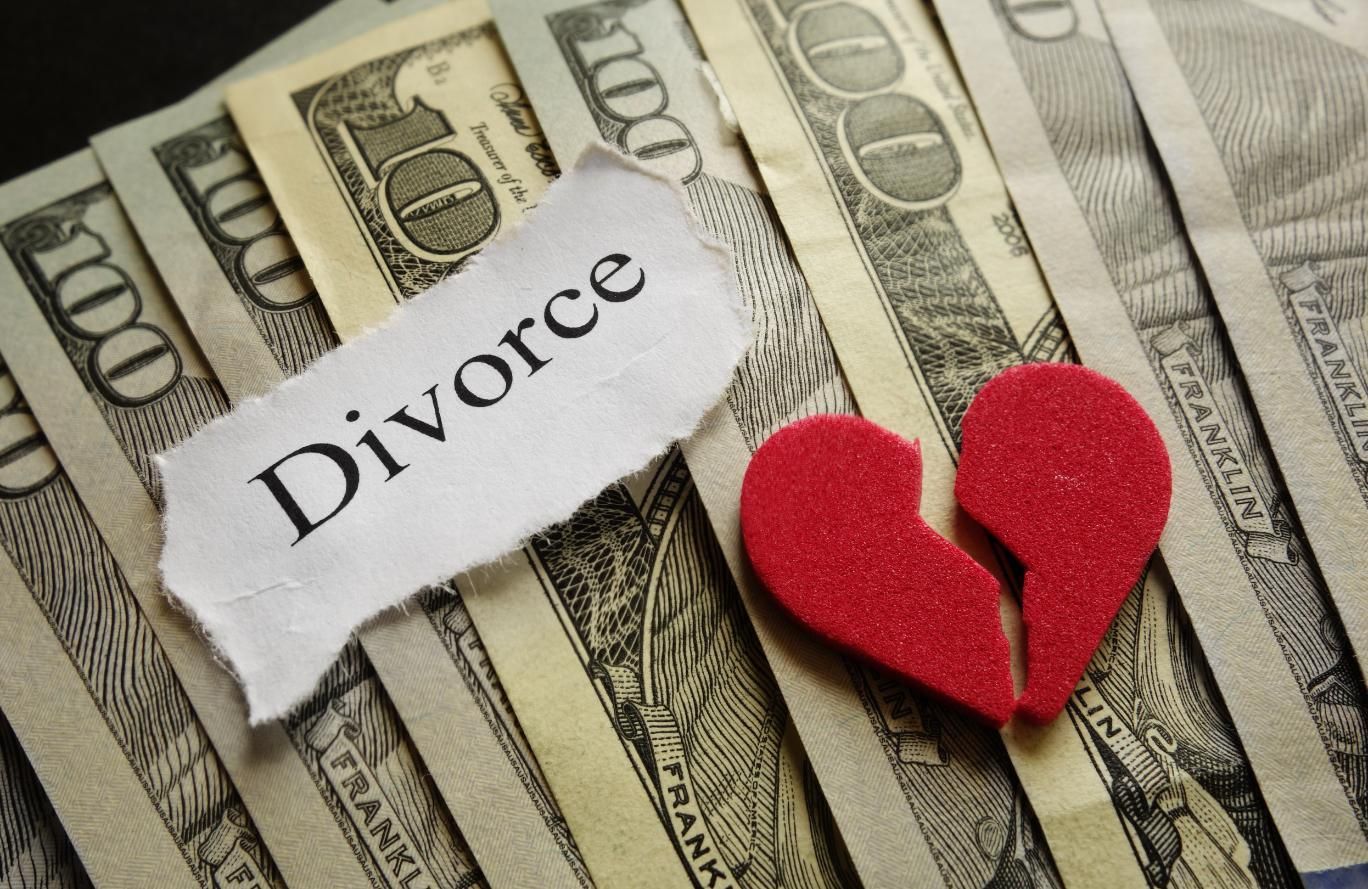 Divorce paper on US dollar bills with a broken red heart symbol