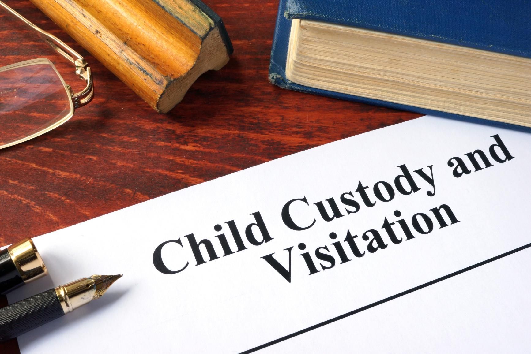 Child custody and visitation document on a desk with a pen and books