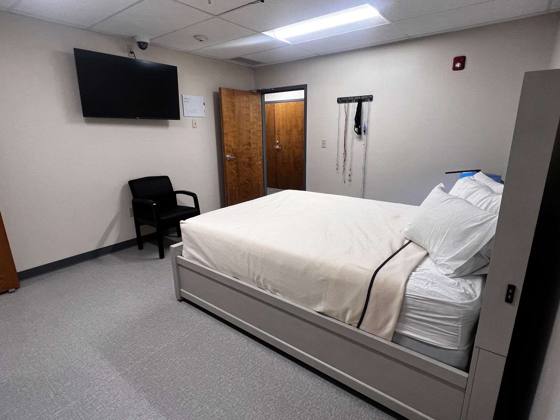 A hospital room with a bed , chair and television | Intrepid Research