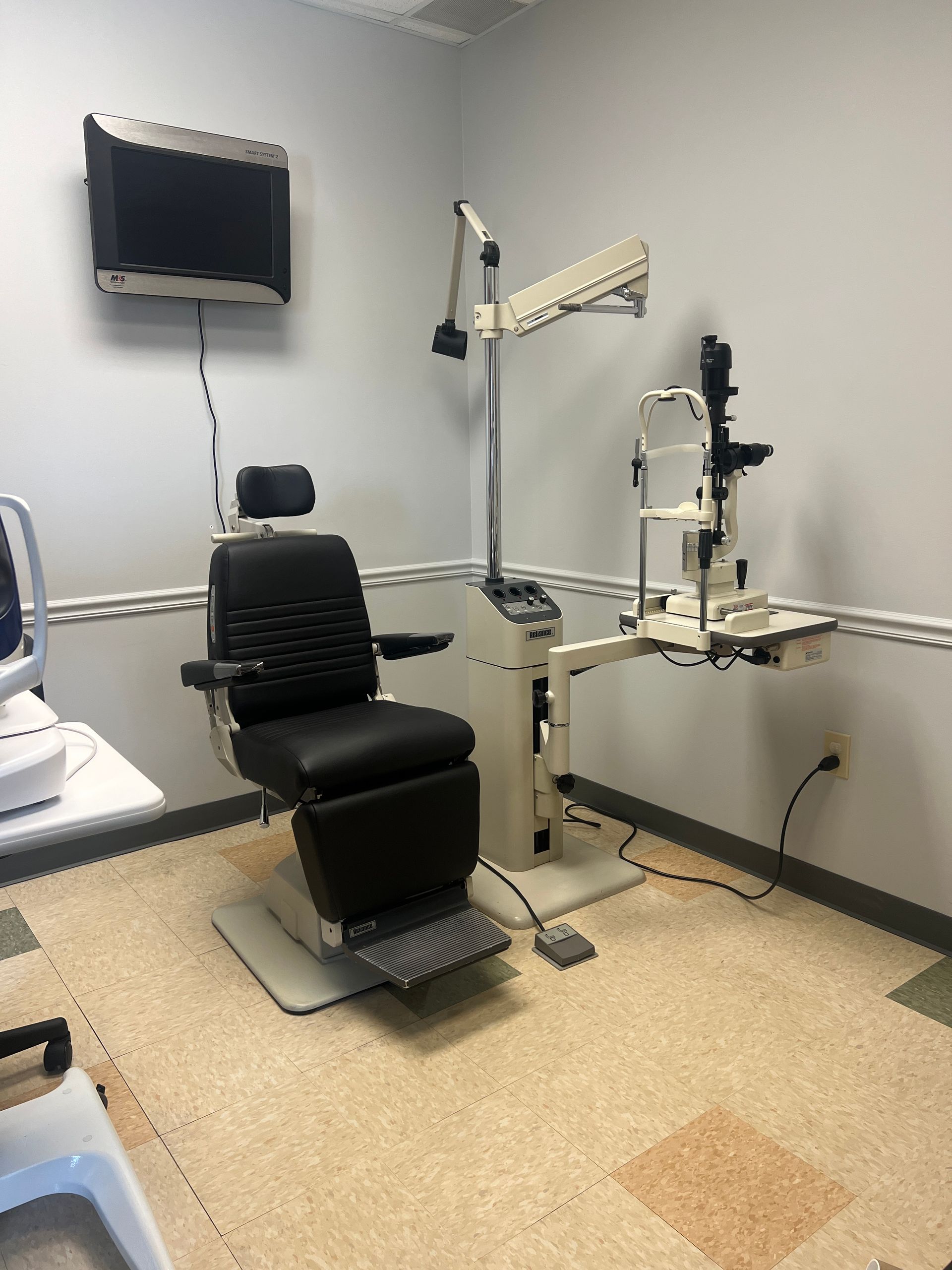 An ophthalmologist 's office with a chair and a television on the wall | Intrepid Research