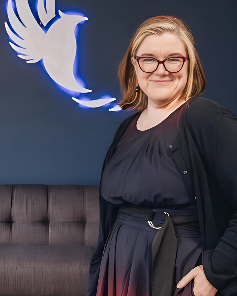A woman wearing glasses is standing in front of a dove sign | Intrepid Research
