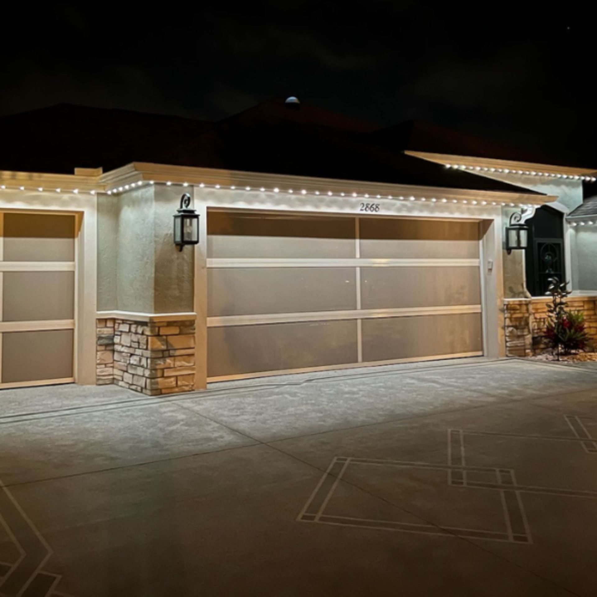 Silvers, Inc. - A modern home at night with glowing garage lights, garage door and the moon.