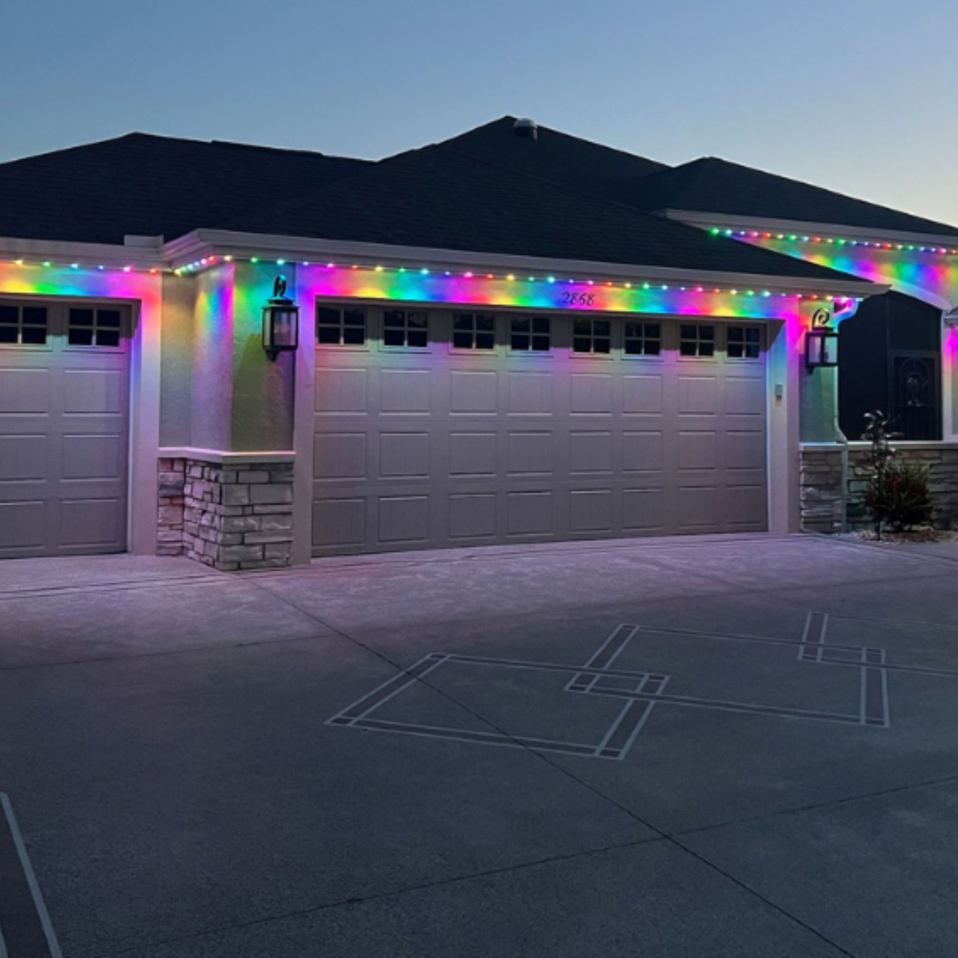 Silvers, Inc. - Garage with colorful rainbow-lit lights along the roofline, with a dark roof, and light-colored walls.