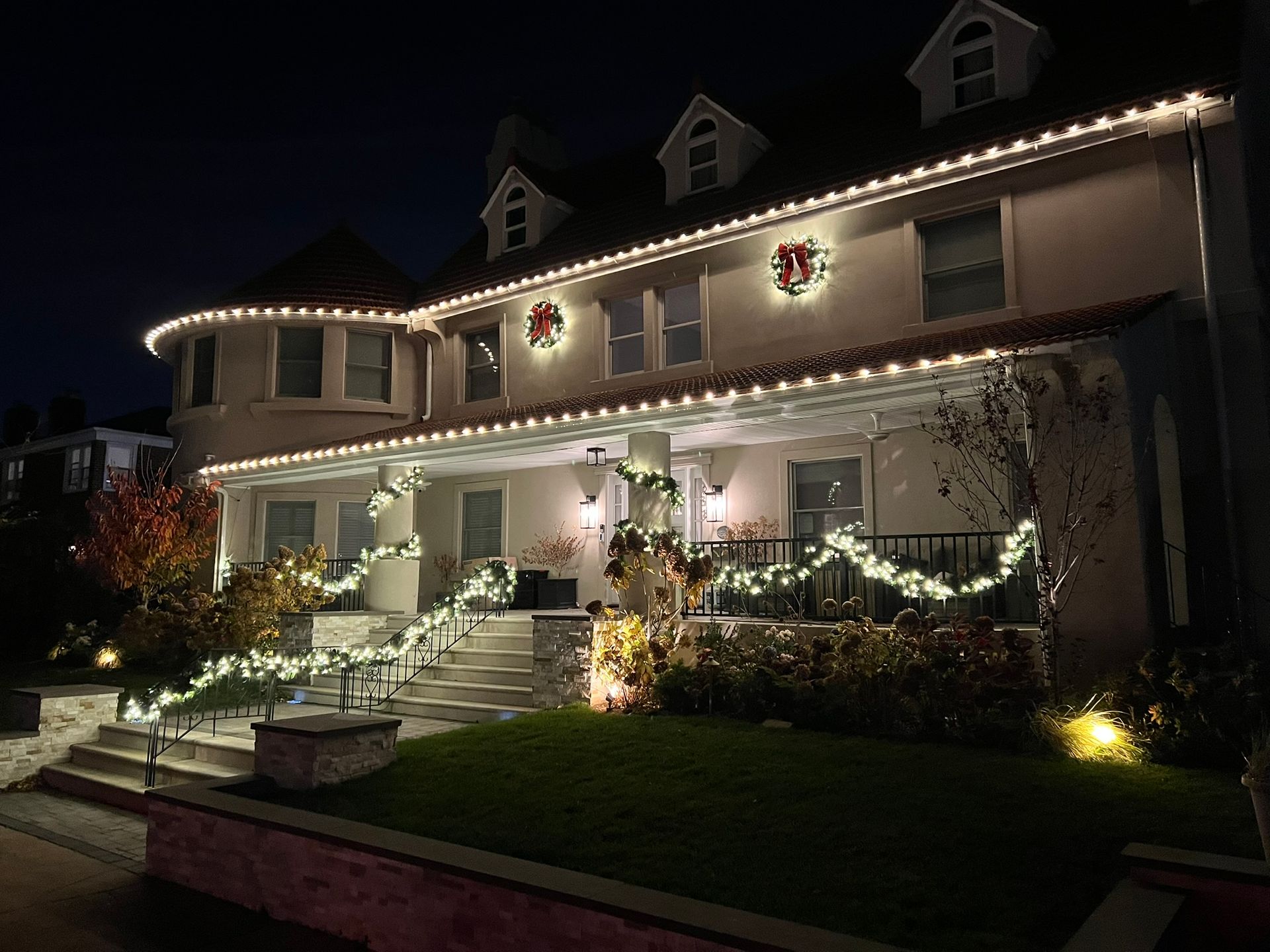 Silvers, Inc. - Large house lit with white Christmas lights, wreaths, and garlands at night.