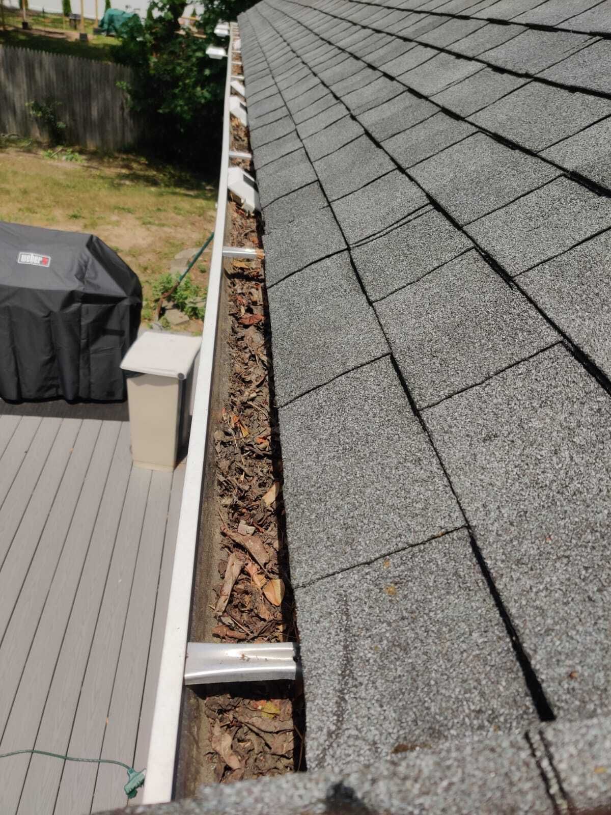 A gutter with leaves on it is sitting on top of a roof
