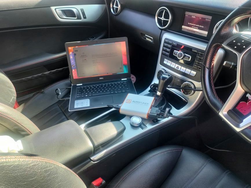A laptop is sitting on the dashboard of a car.