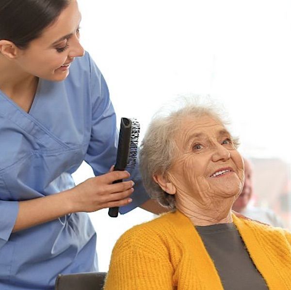 Caregiver helping elderly woman with her hari