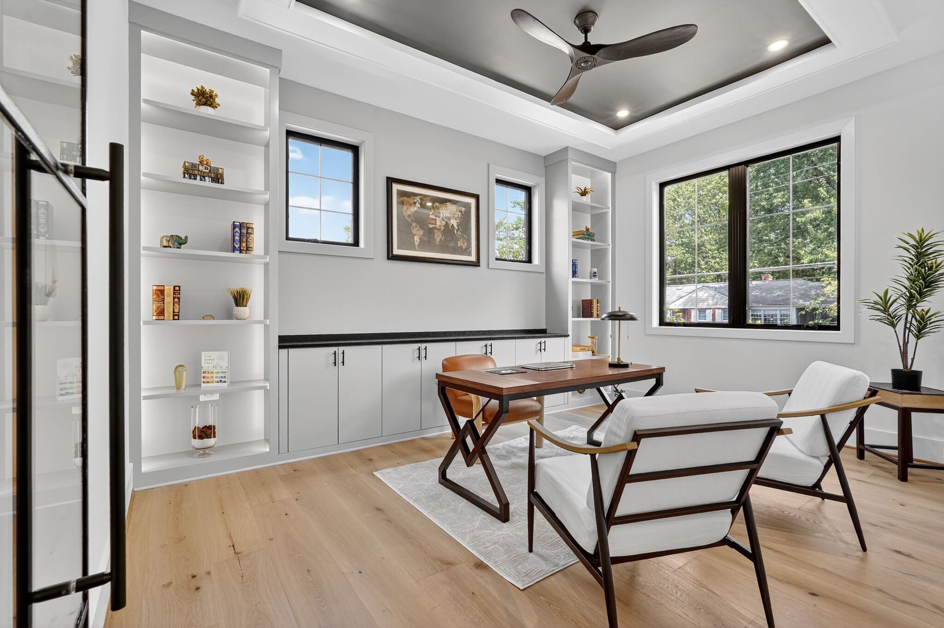 Backyard patio with wicker furniture, large windows, and white house.