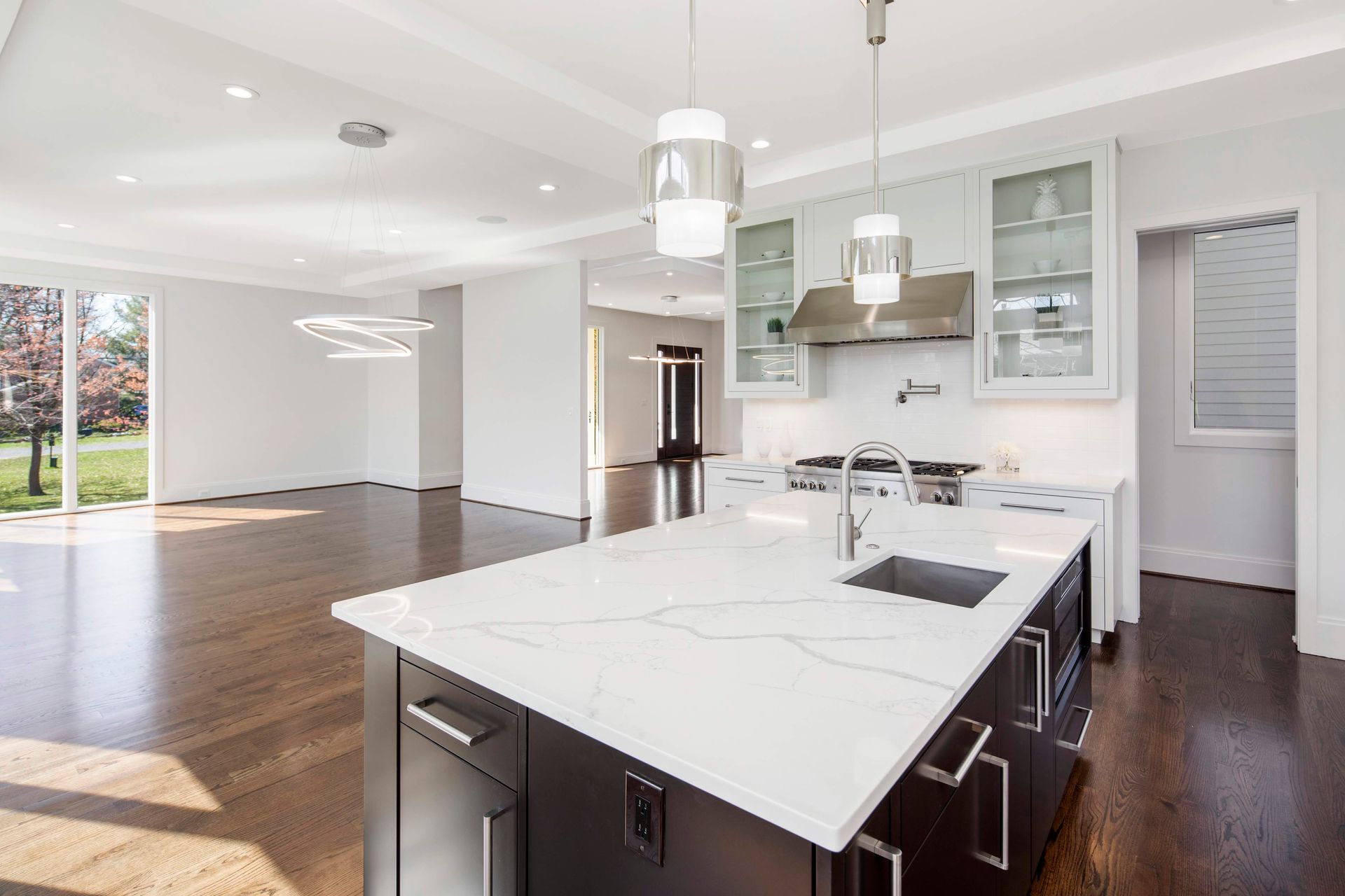 Modern kitchen with white countertops, dark wood cabinets, and pendant lights.