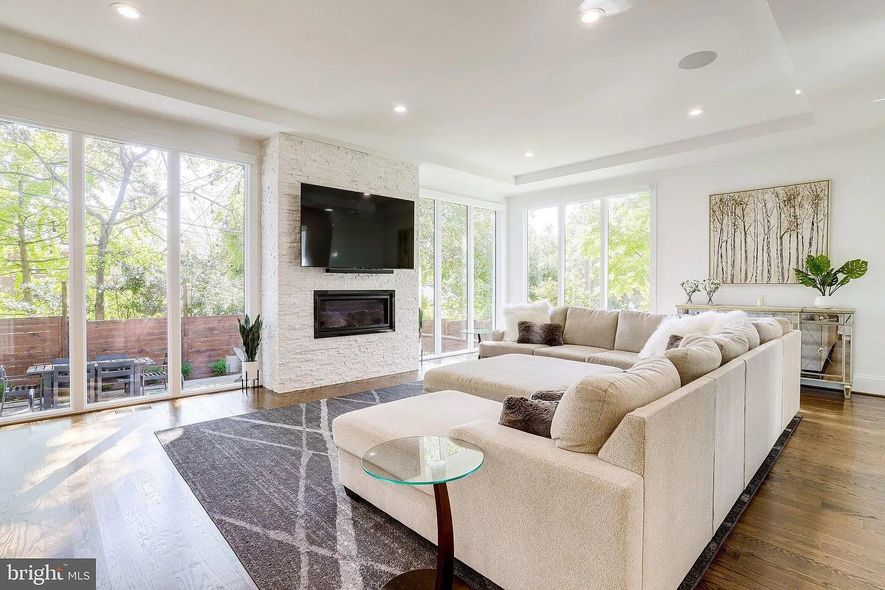 Spacious living room with large windows, fireplace, and beige sectional sofa.