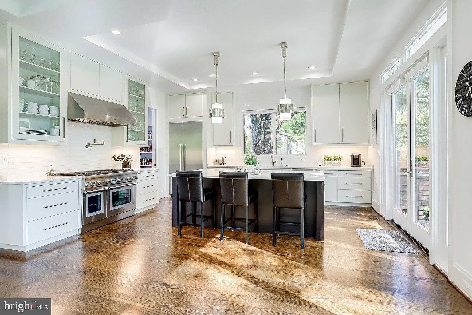 Modern kitchen with white cabinets, stainless steel appliances, and dark island with bar stools.