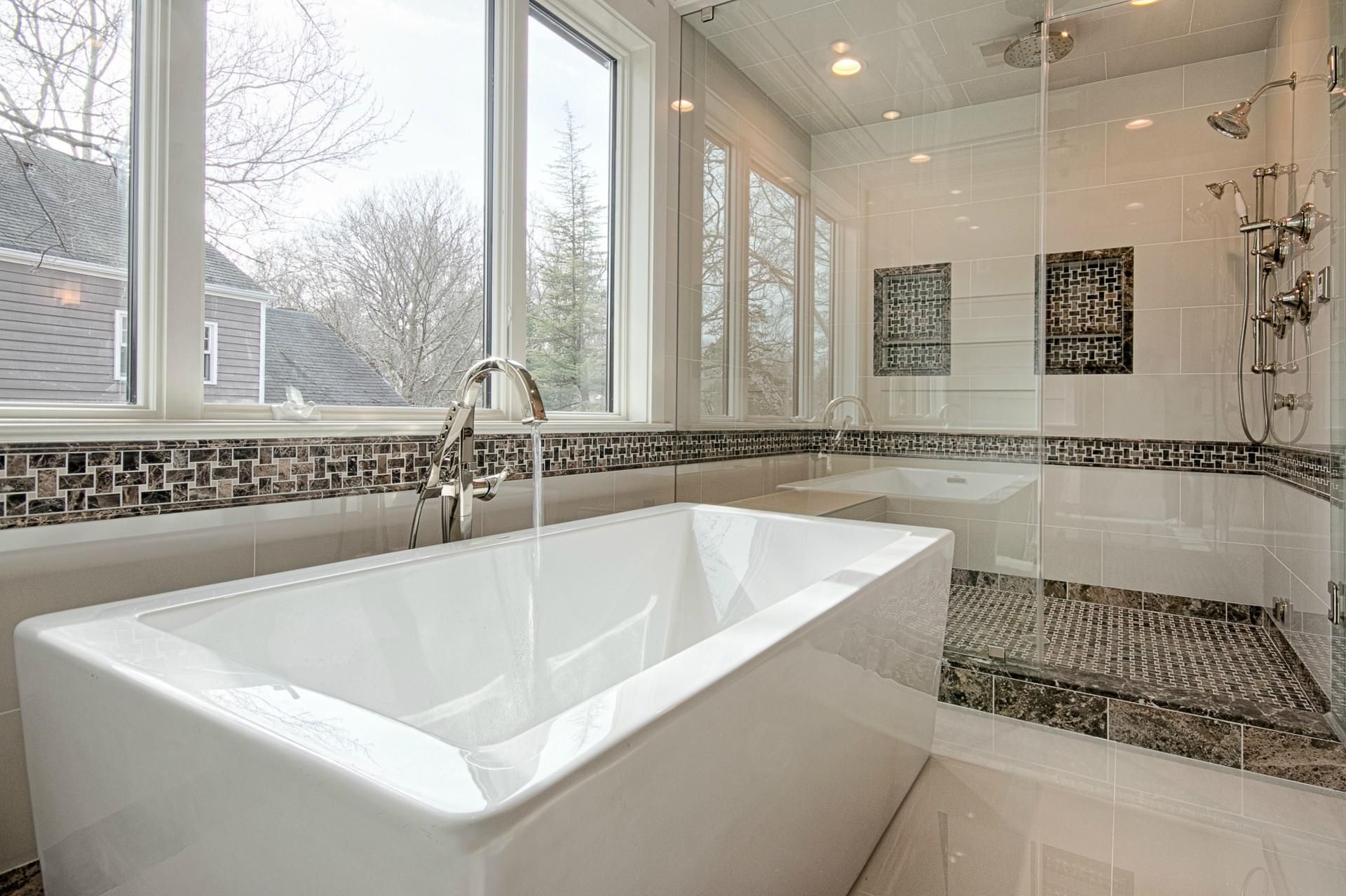 White bathroom with marble shower, vanity, toilet, and towel rack.