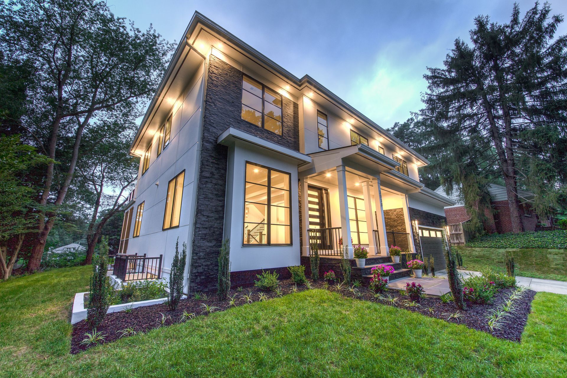 Modern white house with dark framed windows, lawn, and stepping stones.