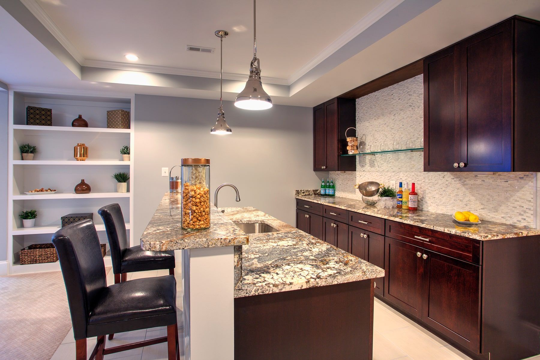 Kitchen with granite countertop, dark cabinets, a built-in bar, and two black bar stools.