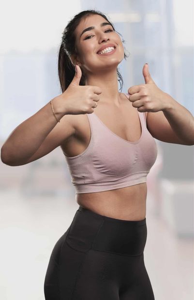 Two women pose in front of a reception desk, one in scrubs, the other in a blue dress and lab coat.