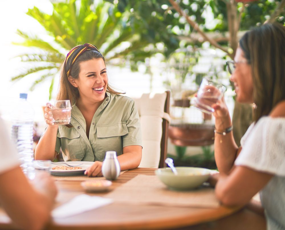 A group of women are sitting at a table drinking water and eating food.
