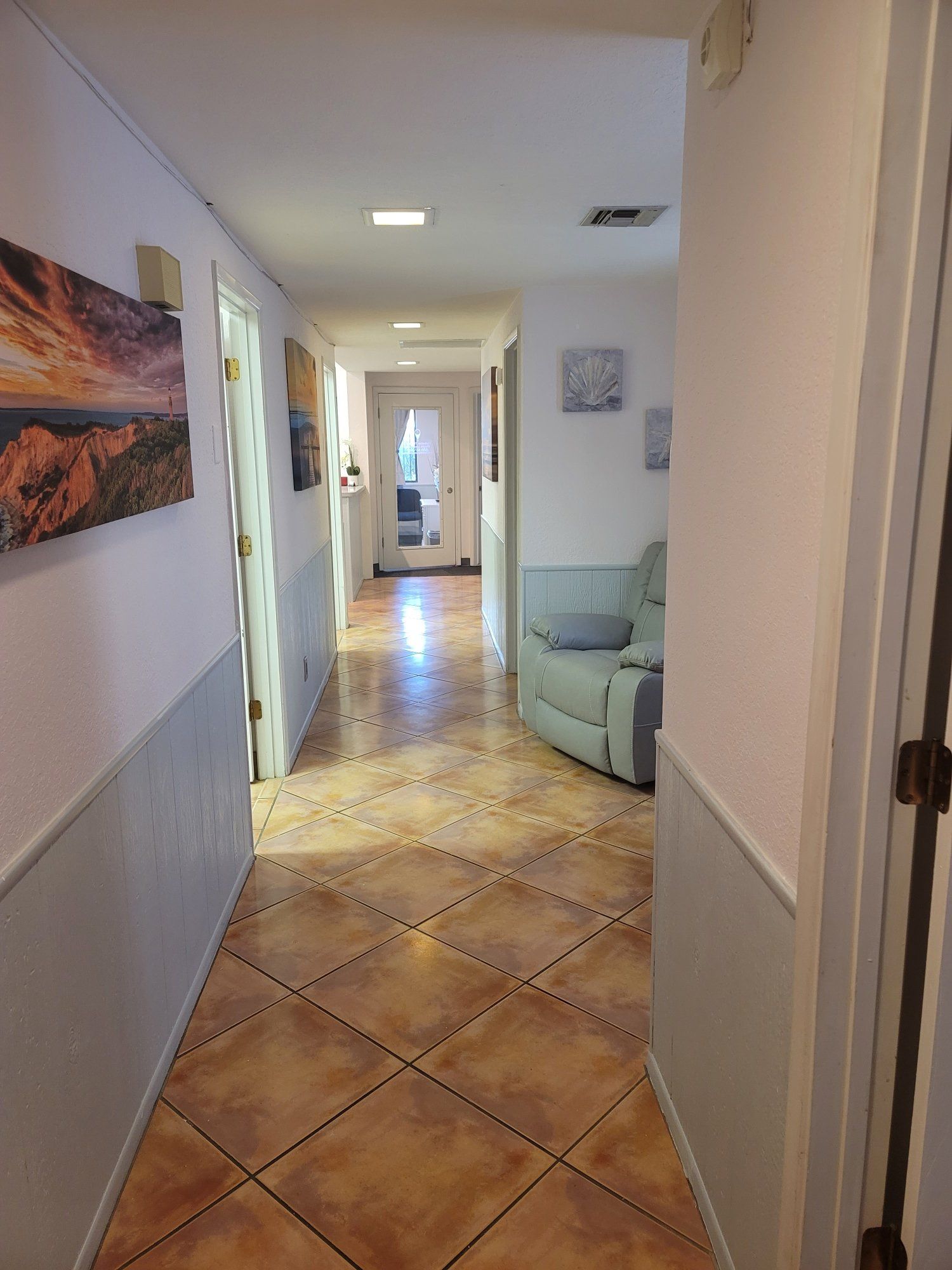 A long hallway with a couch and a painting on the wall.