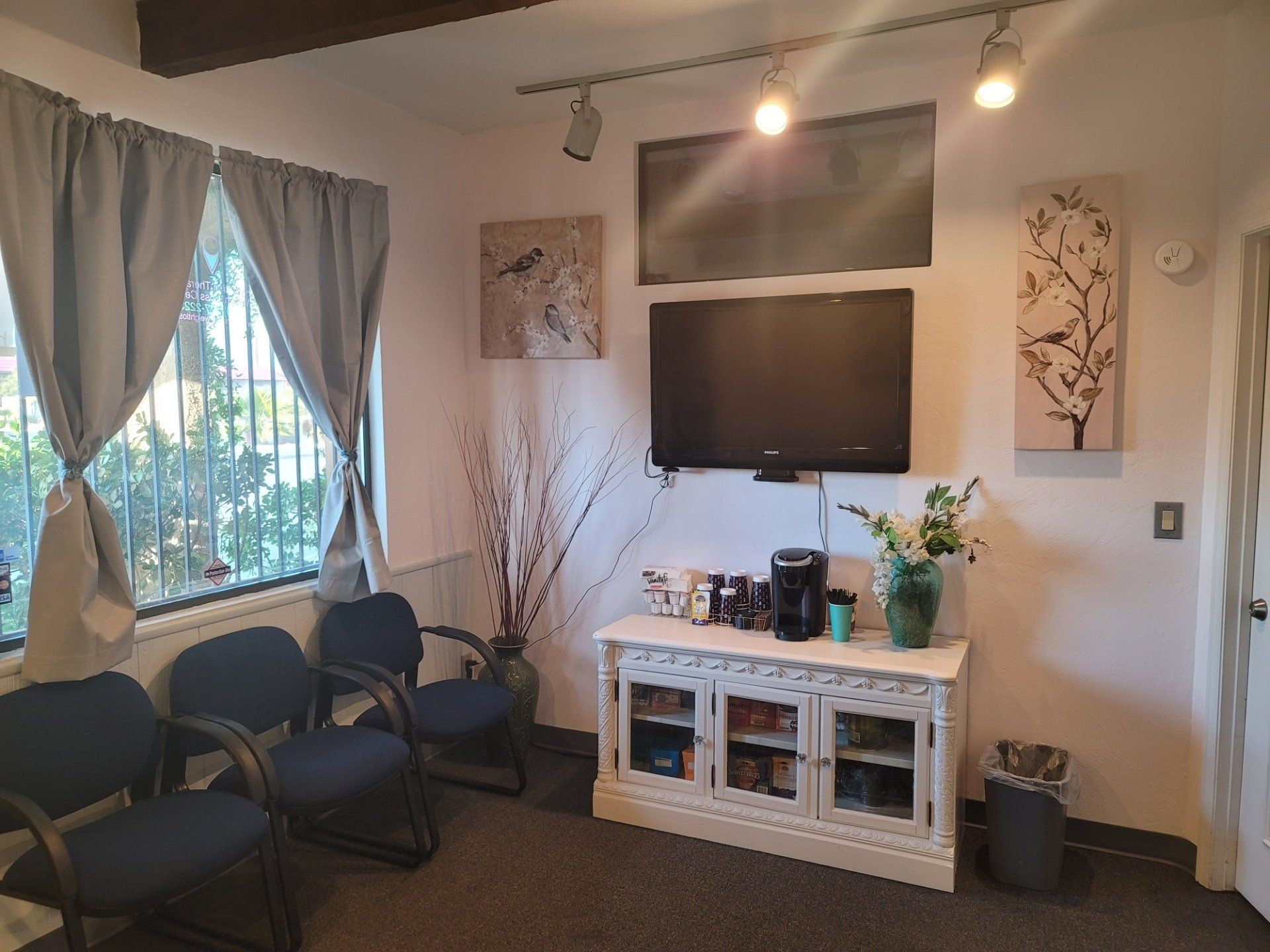 A waiting room with chairs and a flat screen tv on the wall.