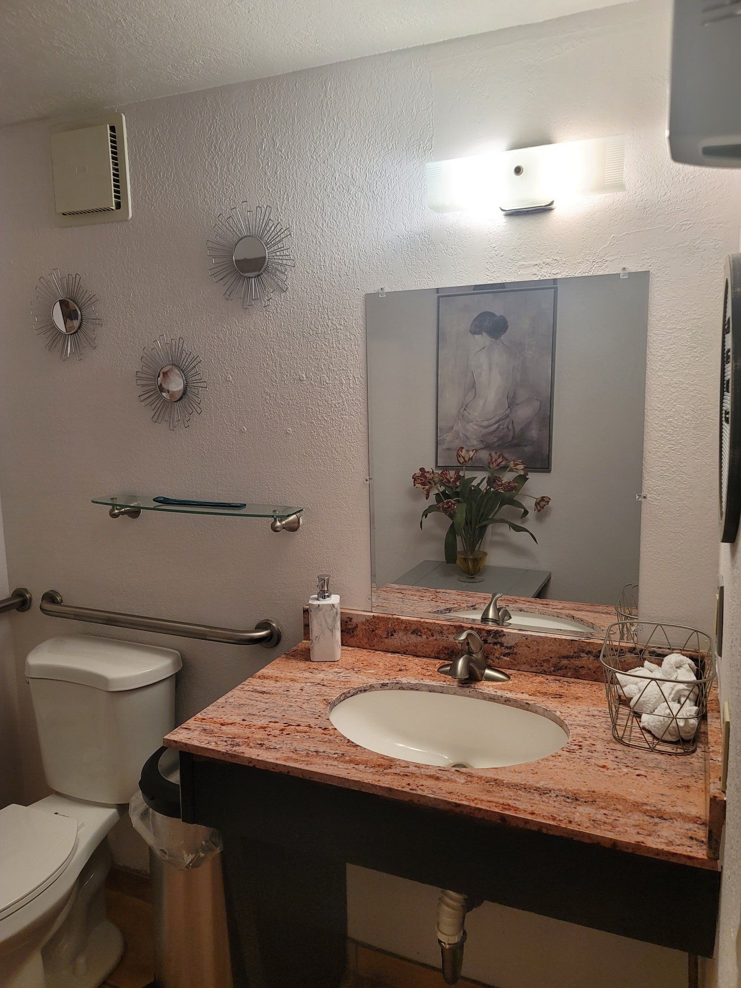 A bathroom with a sink , toilet and mirror.