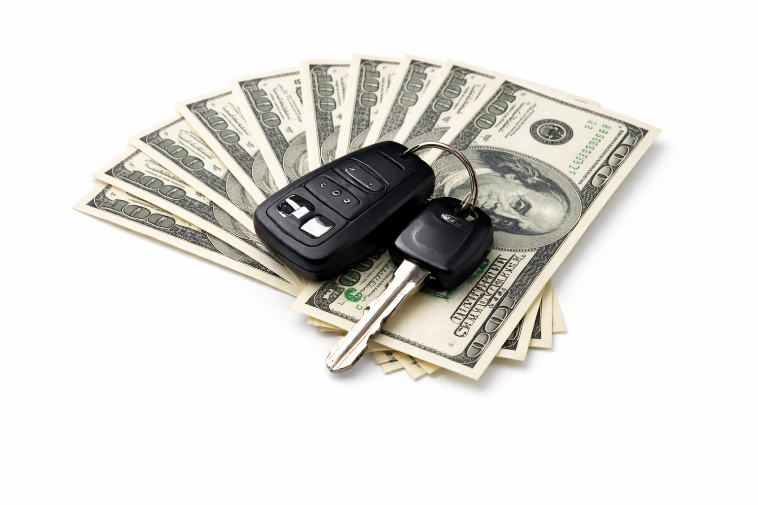 A car key fob and physical key resting on top of a fanned-out stack of hundred-dollar bills.