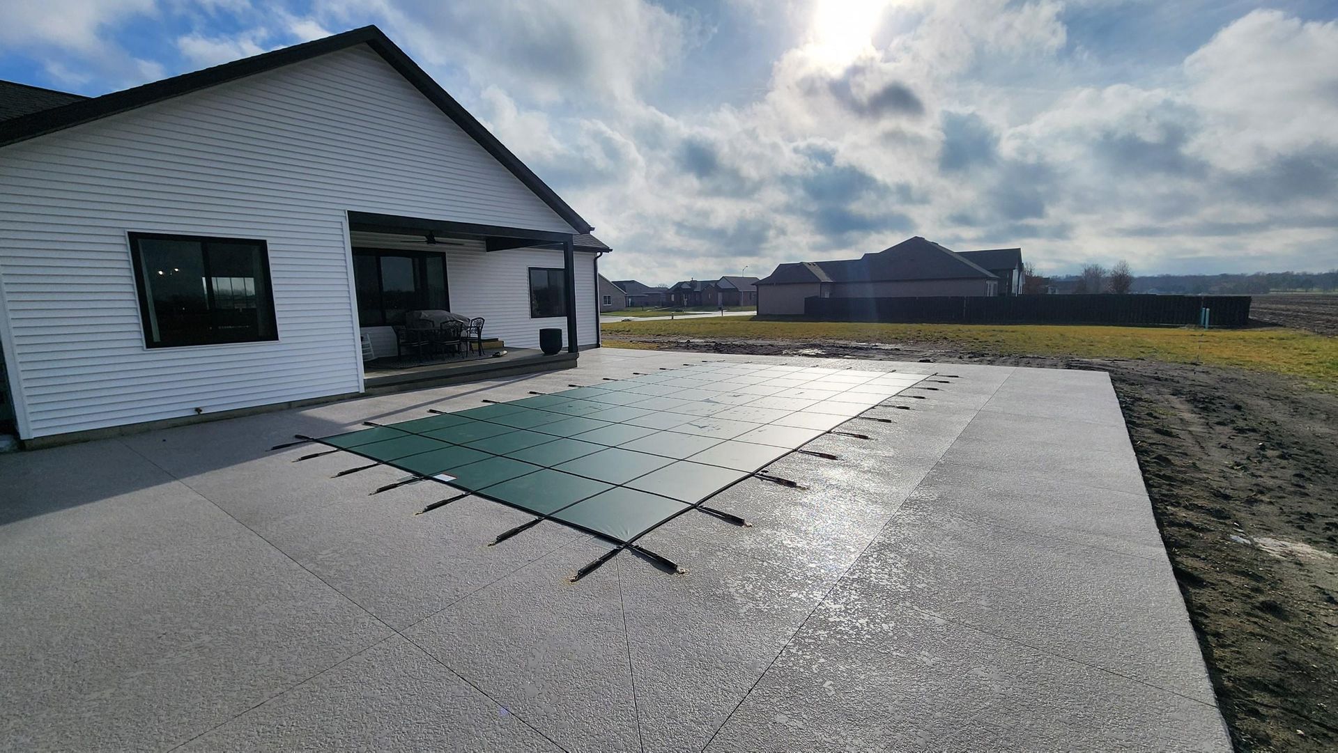 House with a covered pool in a concrete patio on a sunny day.