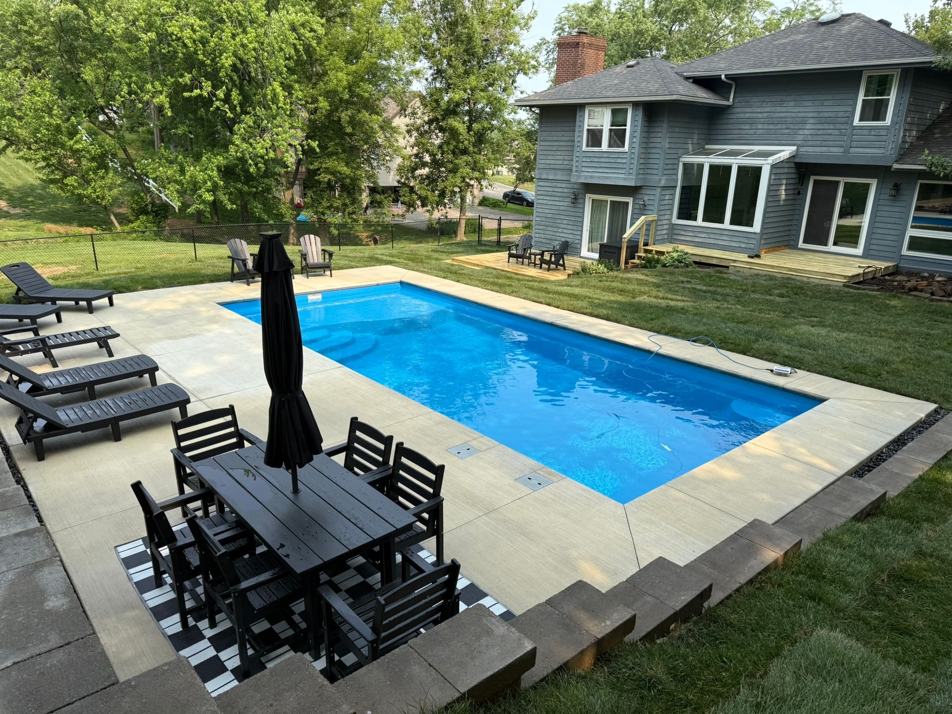 Backyard pool with patio furniture and a house.