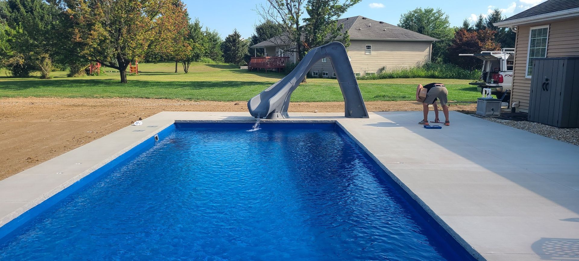 Rectangular pool with slide and a person preparing to swim in the pool.