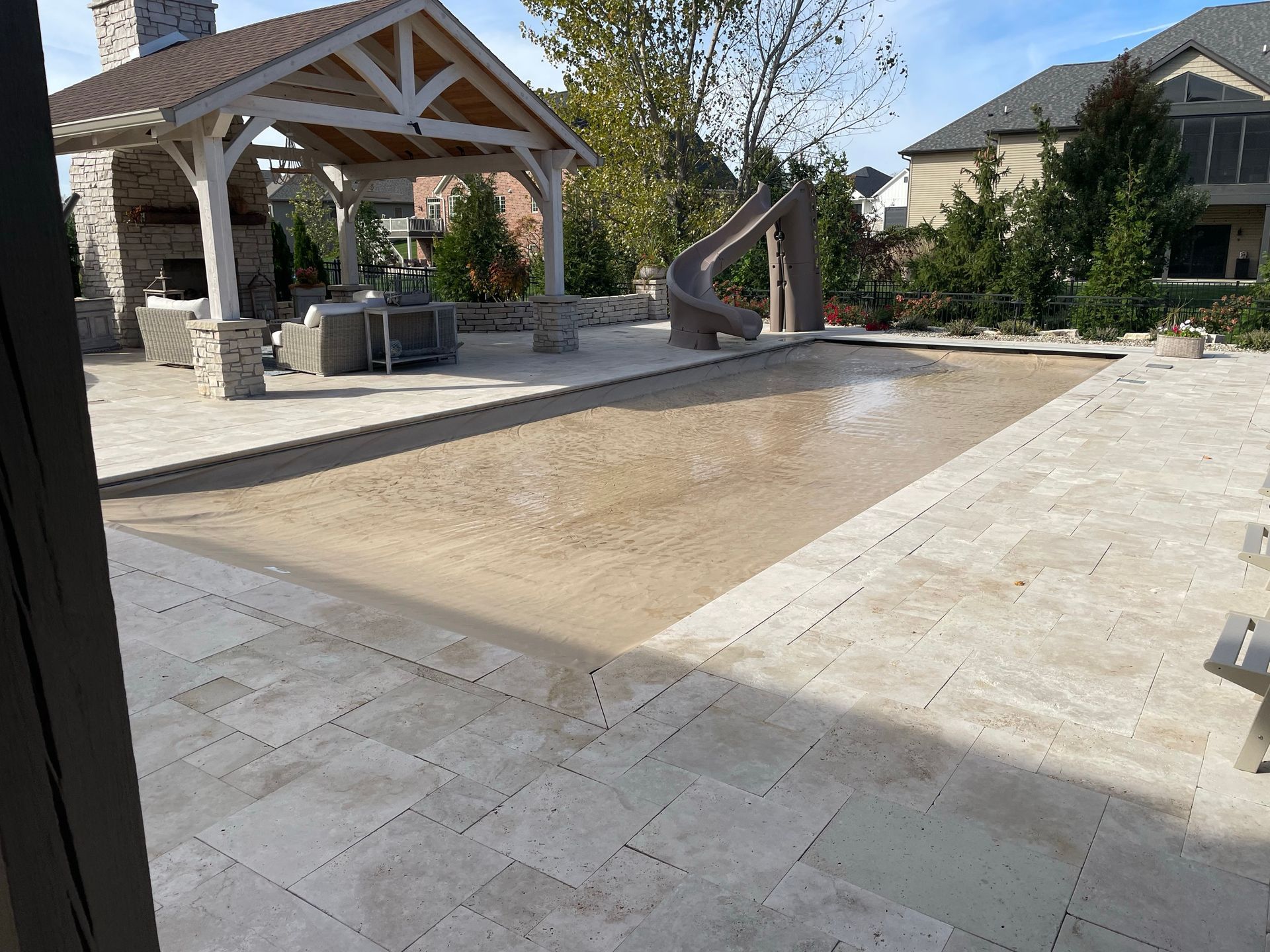 Backyard pool with a tan pool cover, patio, gazebo, and slide.
