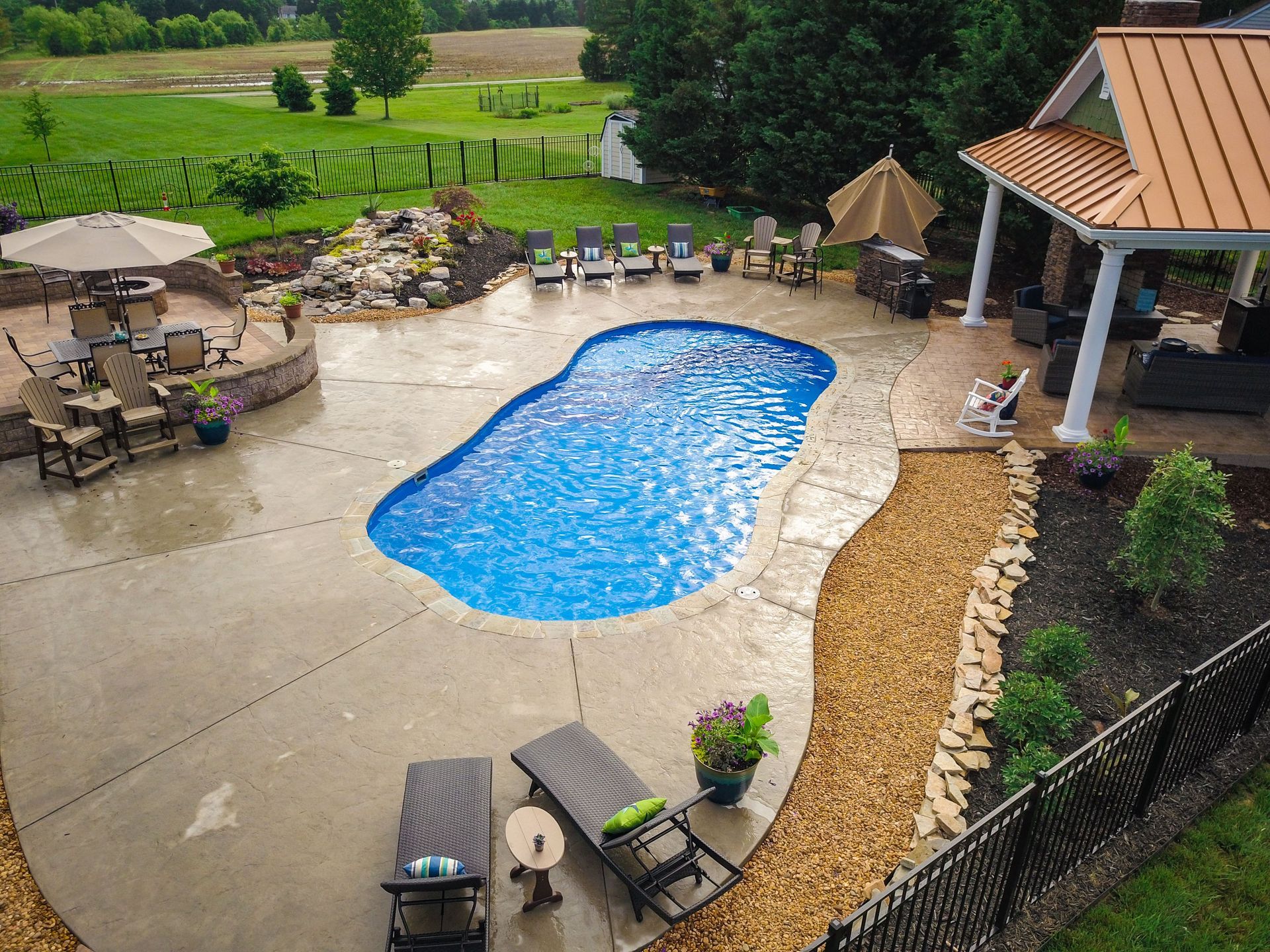 Backyard pool with patio, lounge chairs, and landscaping.