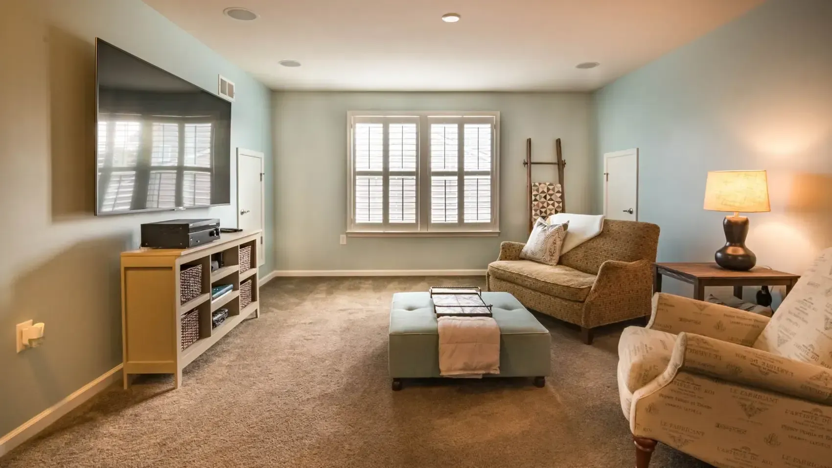 A living room with a couch , chairs , and a flat screen tv.