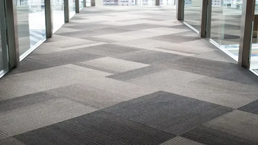 A long hallway with a carpeted floor and a lot of windows.