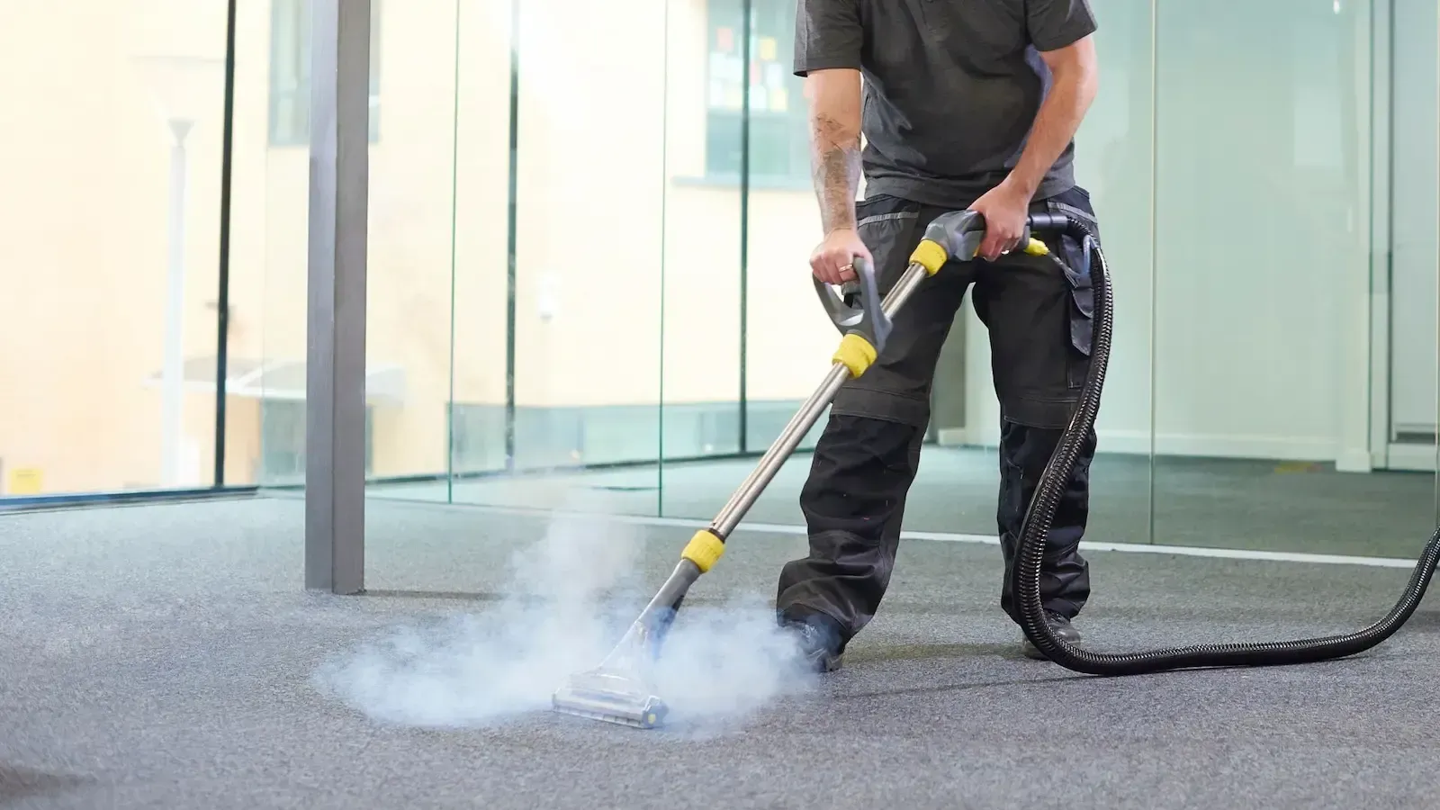 A man is cleaning a carpet with a steam cleaner.