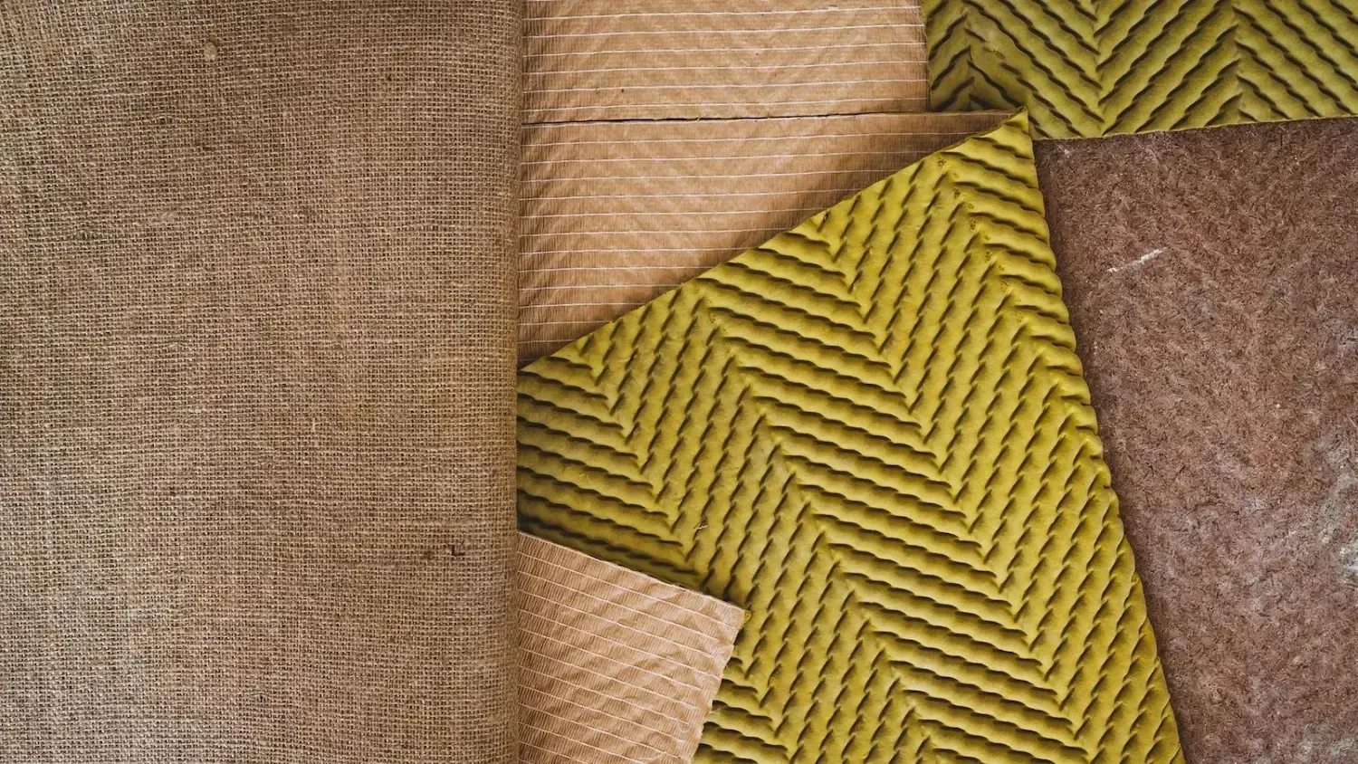 Close-up of overlapping woven and textured fabrics in brown, tan, yellow, and rust tones