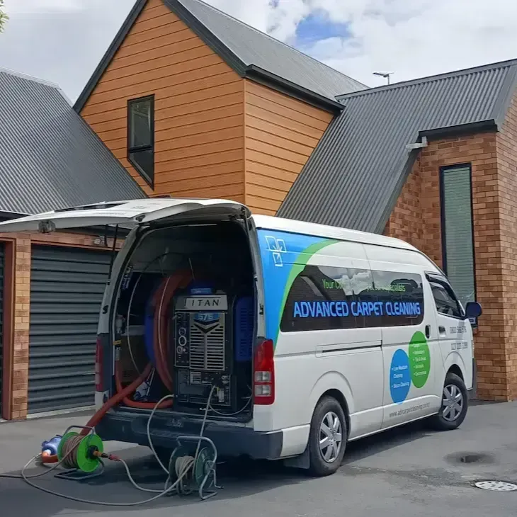 A white van with the back door open is parked in front of a house.