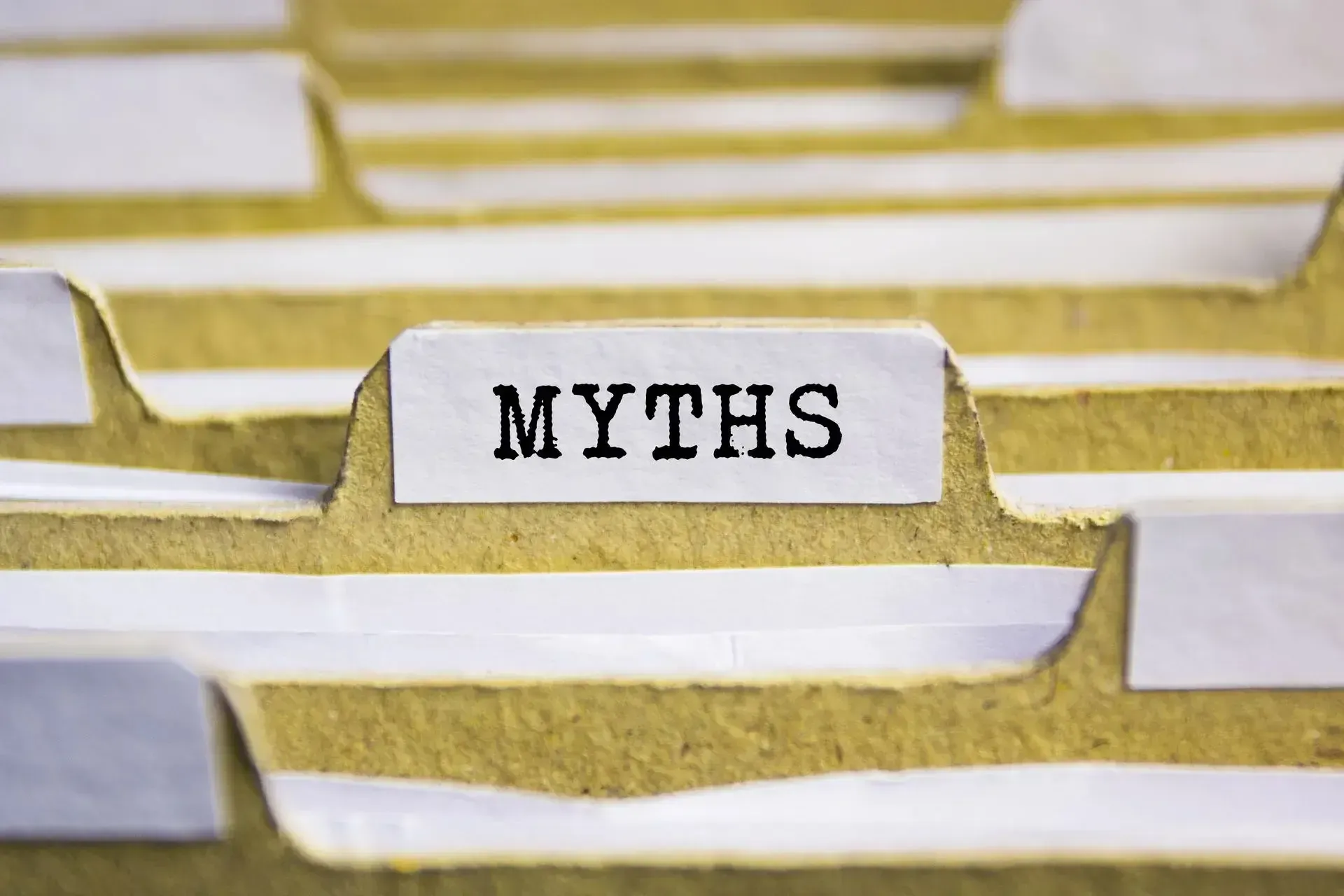 The word myths is written on a piece of paper in a file folder.