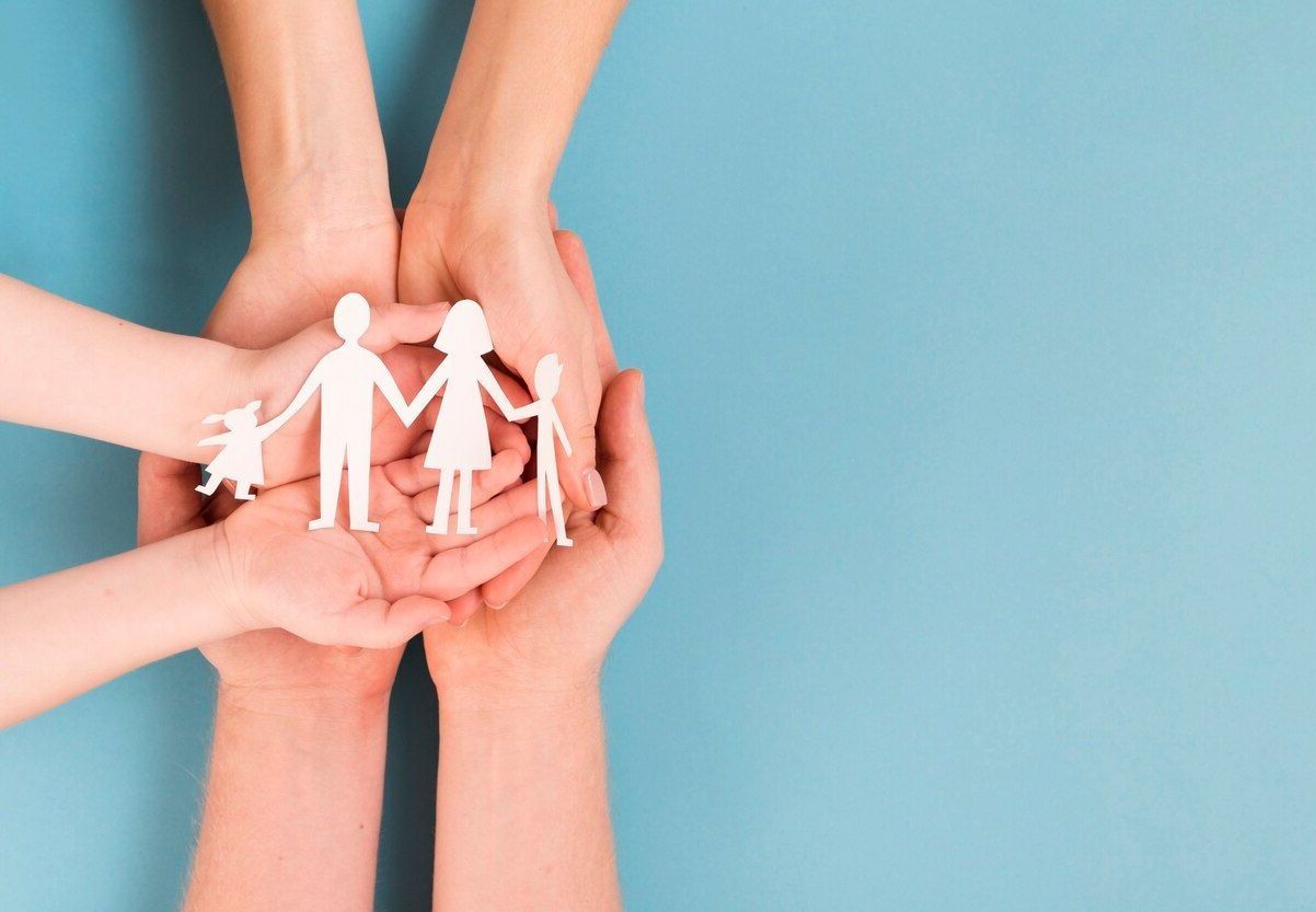 Un grupo de personas sostiene una familia de papel en sus manos.