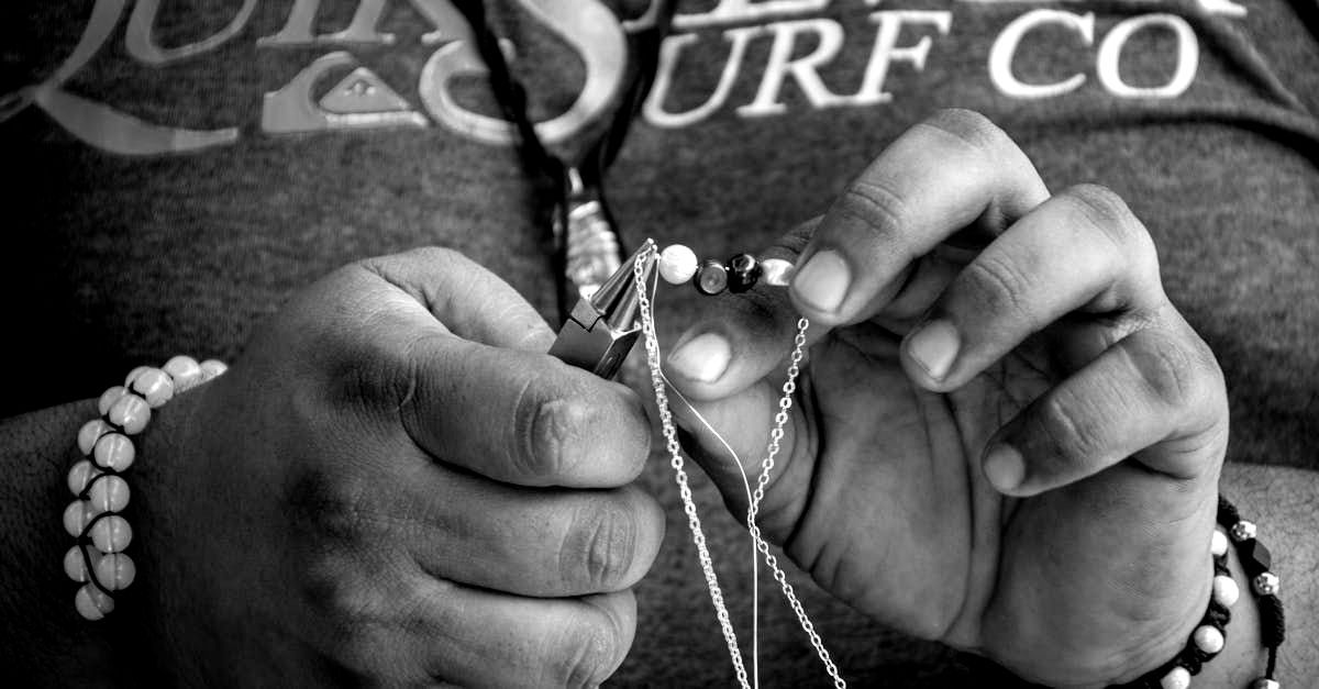 Una persona está haciendo un collar con cuentas y perlas.