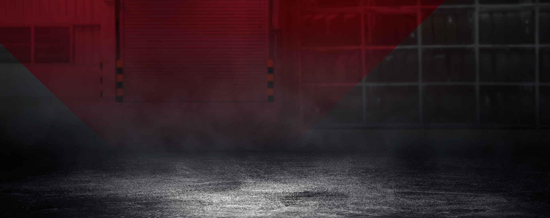 Dark asphalt floor with fog in front of a red, black, and white industrial background. | Good Guys Auto Care & Tires