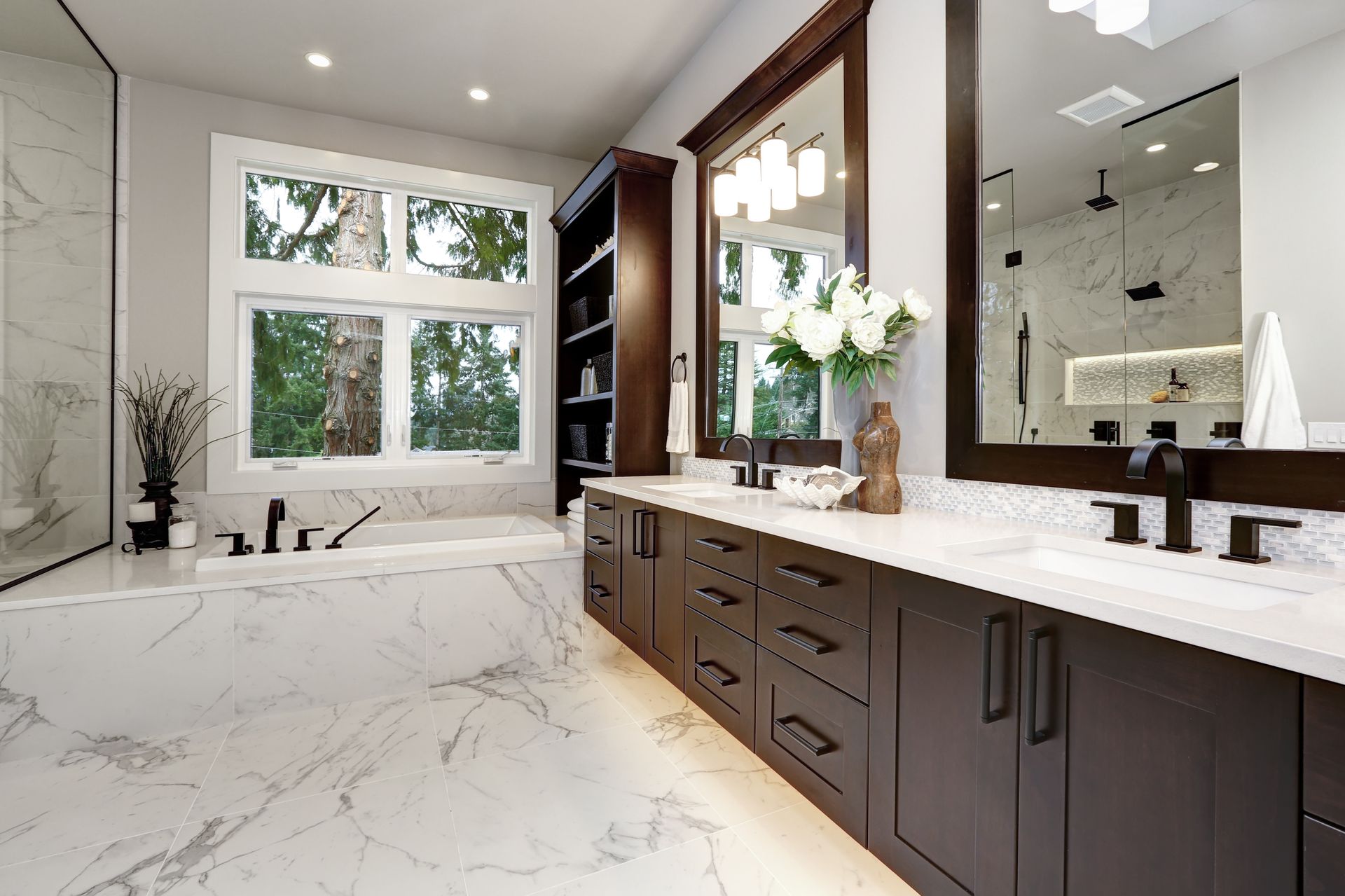 Bathroom with white marble, dark cabinets, a large window, and double sinks.